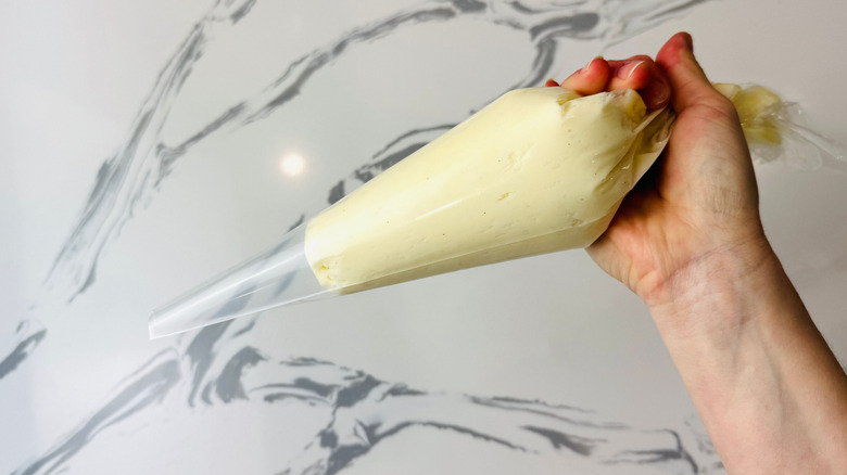 Hand holding piping bag of frosting