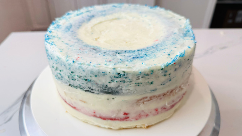 Lightly frosted red, white, and blue cake on stand
