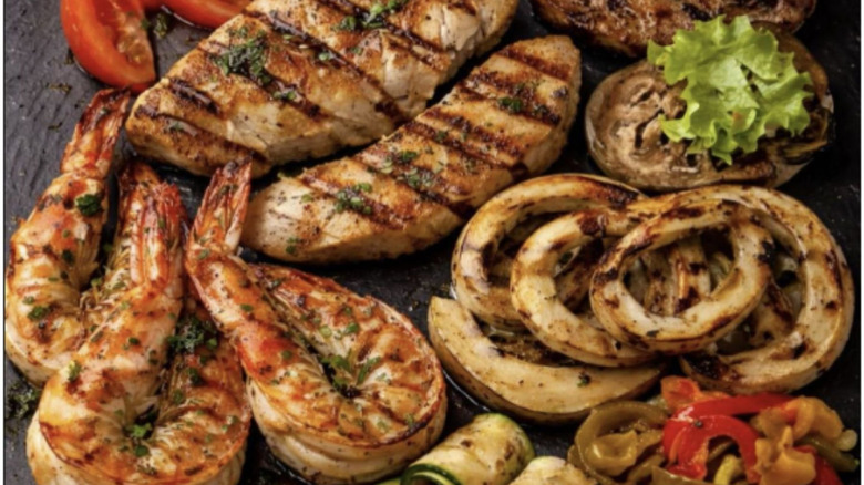 A selection of mixed Italian-style cookout food, including various meats, fish, and peppers