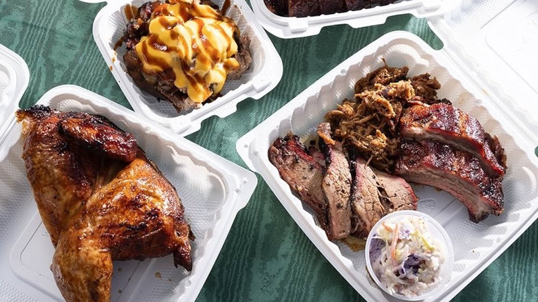 Trays with BBQ chicken, ribs, and brisket on a picnic table