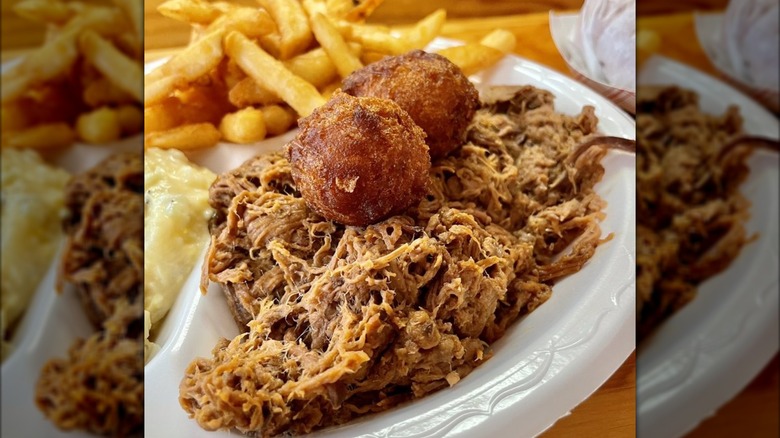 Plate with pulled beef brisket, hush puppies, and fries