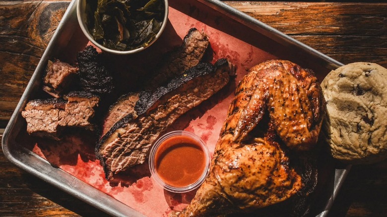 Tray of BBQ chicken, brisket, collard greens, and a cookie