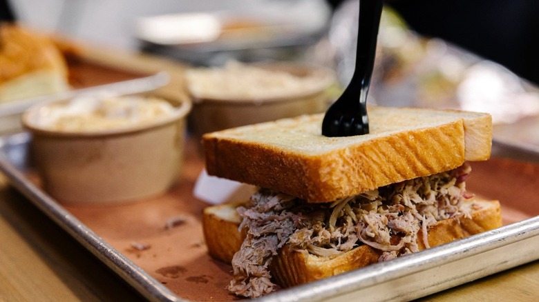 Pulled pork sandwich with sides blurred in the background