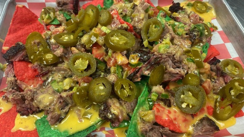 Brisket nachos with jalapeños and cheese on a metal tray