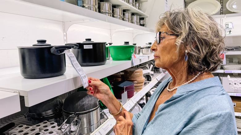 A woman evaluating price tags of kitchenware