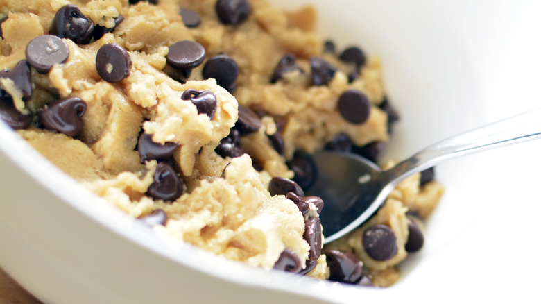 Closeup of scooping raw cookie dough out of a white bowl with a spoon