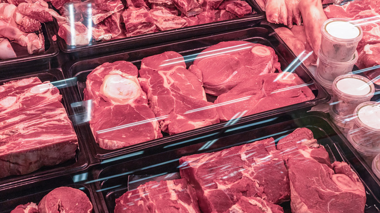 A variety of cuts of red meat, packaged and chilled in a glass case