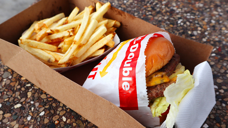 Andrew Zimmern displays a burger on a fork