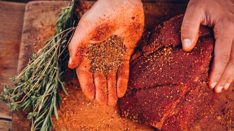 hands putting spice rub on steak