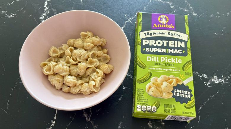 Shell mac and cheese in bowl next to Annie's Dill Pickle mac and cheese box