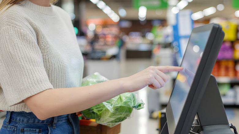 person in self checkout tapping screen