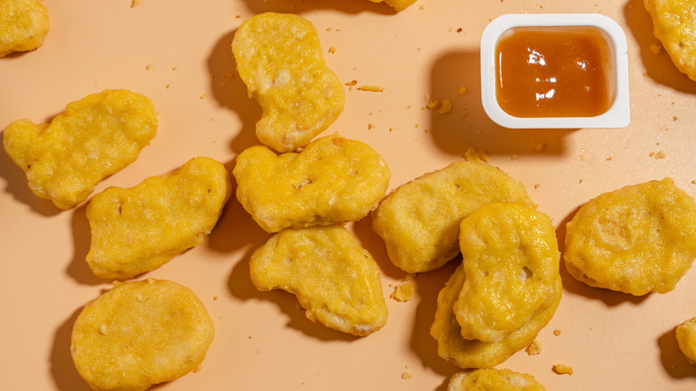 Chicken nuggets on an orange background with a dipping sauce