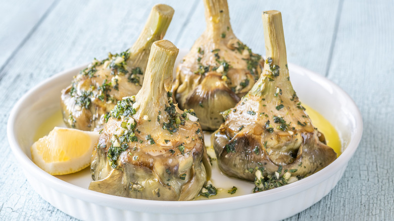 roman-style artichokes in a white round dish with lemon