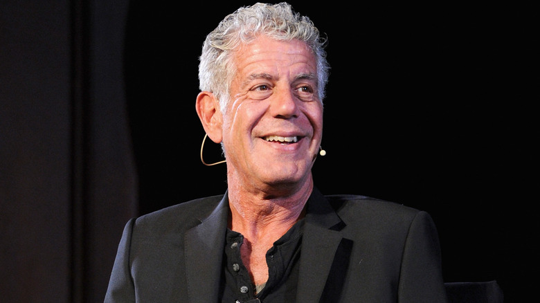 Anthony Bourdain smiling, sitting in an interview chair