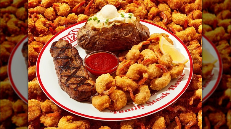 A plate of steak, shrimp, and a baked potato on a Sizzler plate