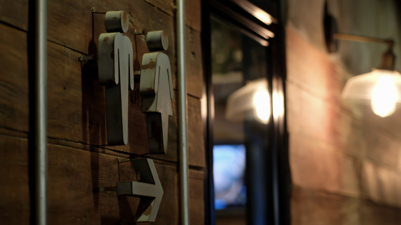 A male and female figure on a wall above an arrow directing you to restrooms