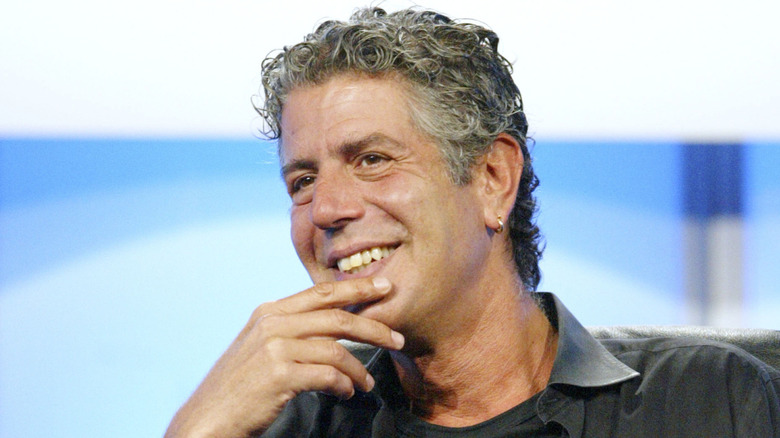 Anthony Bourdain, smiling with a hand to his chin
