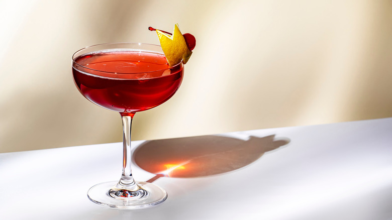 A Manhattan cocktail in a coupe glass with a lemon peel garnish.