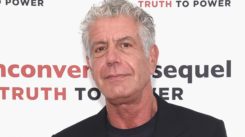 Anthony Bourdain smiles in black blazer and shirt