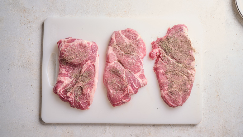 seasoning pork steaks on a table