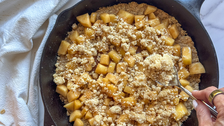 hand adding streusel to pan