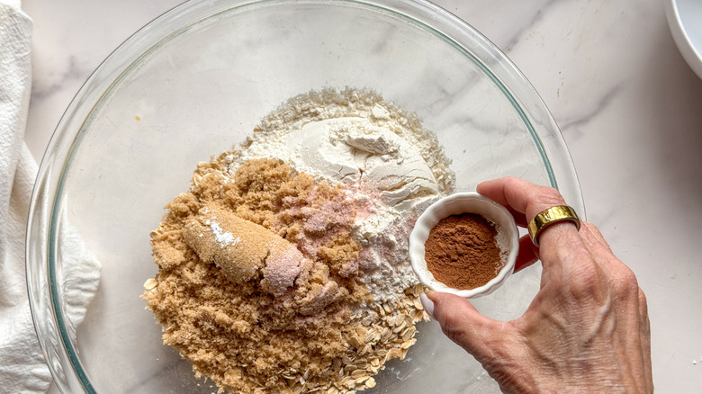 hand adding cinnamon to bowl