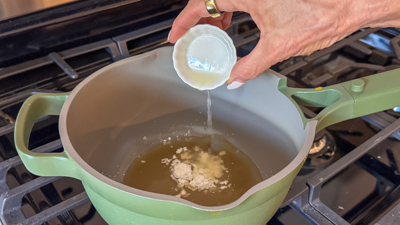 hand adding lemon juice to pot