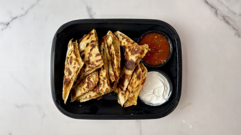Applebee's chicken quesadillas, sour cream, and salsa in a to-go container