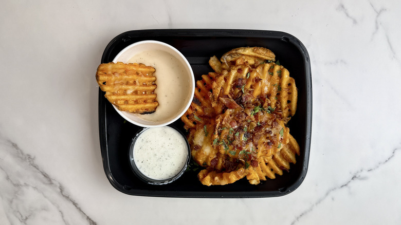 Applebee's brew pub loaded waffle fries, beer cheese, and ranch dip in a to-go container