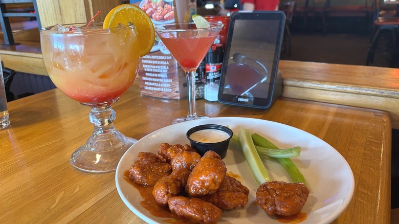 Two Applebees cocktails next to plate of boneless wings on wooden table