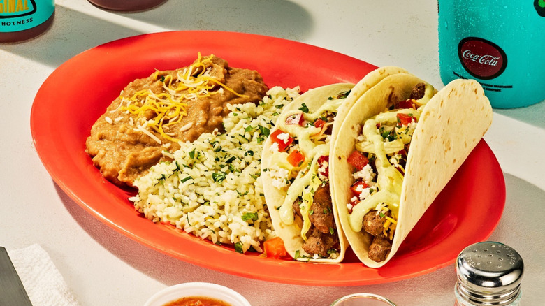 Tacos, rice, and beans from Fuzzy's Taco Shop on red plate