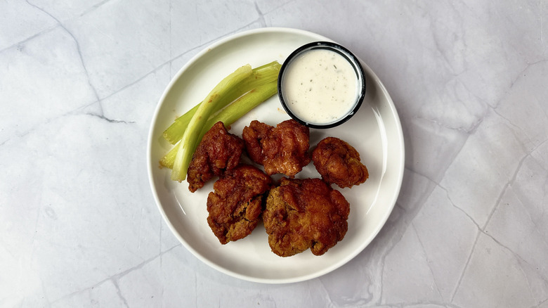 Applebee's boneless wings on a white plate with celery and cup of ranch