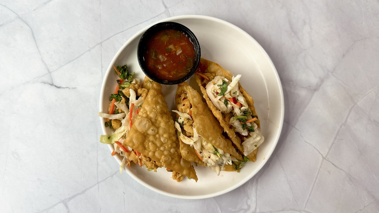 Applebee's Chicken Wonton Tacos on a white plate with cup of salsa