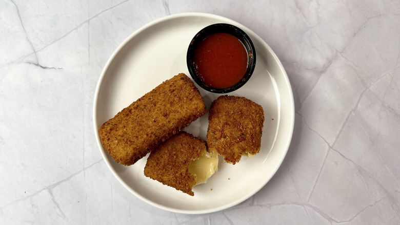 Chili's fried mozzarella on a white plate with cup of marinara