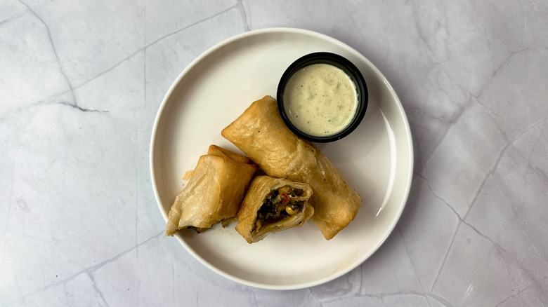 Chili's Southwest egg rolls on a white plate with cup of ranch