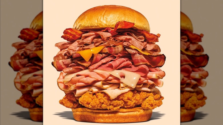 Extremely tall stacked meaty sandwich with cheese.