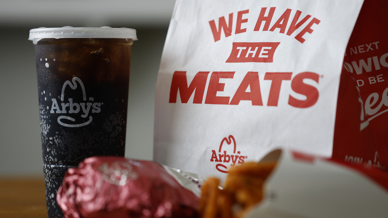 Arby's fast food items, including a cola, by a brand paper bag.