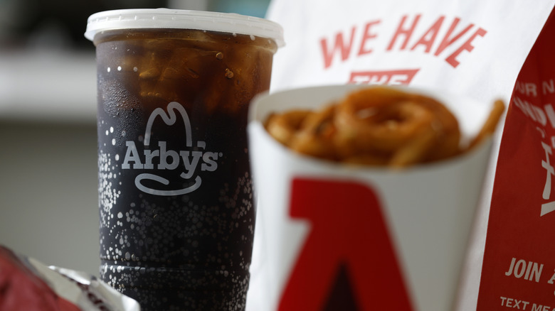 Arby's soda and curly fries sitting in front of a bag