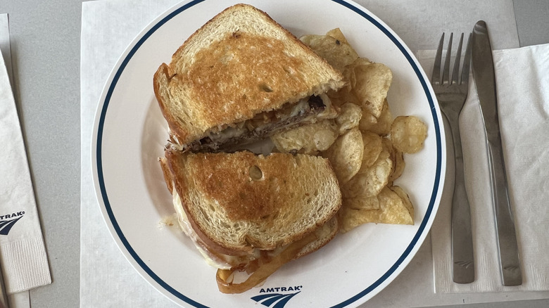 Patty melt and kettle chips on a white Amtrak plate.