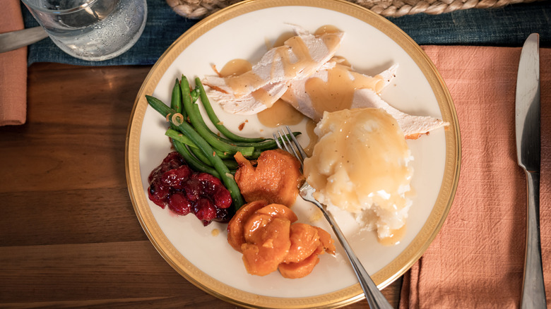 Thanksgiving meal served on a white plate with golden rim