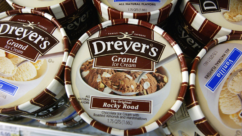 The freezer of a grocery store stocked with Dreyer's ice cream with the rocky road flavor positioned in the center of the frame