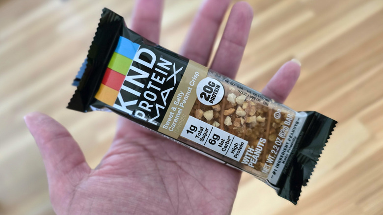 A woman holding a KIND Bar in her hand