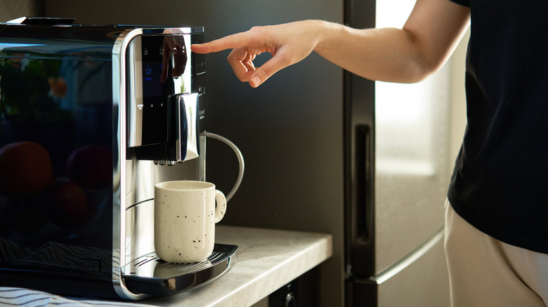 A person pressing a button on a coffee maker