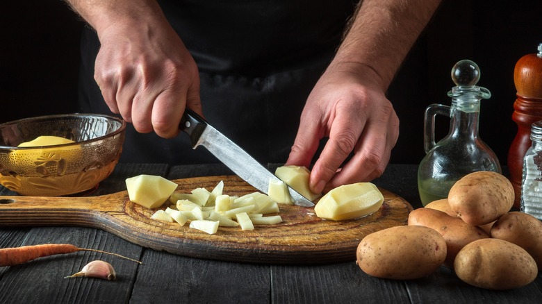 Chef cutting raw potatoes