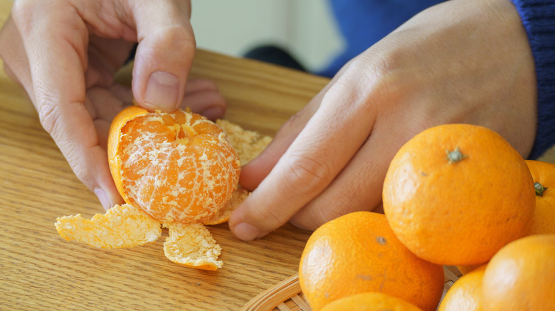 Someone peeling satsuma mandarin oranges on a counter