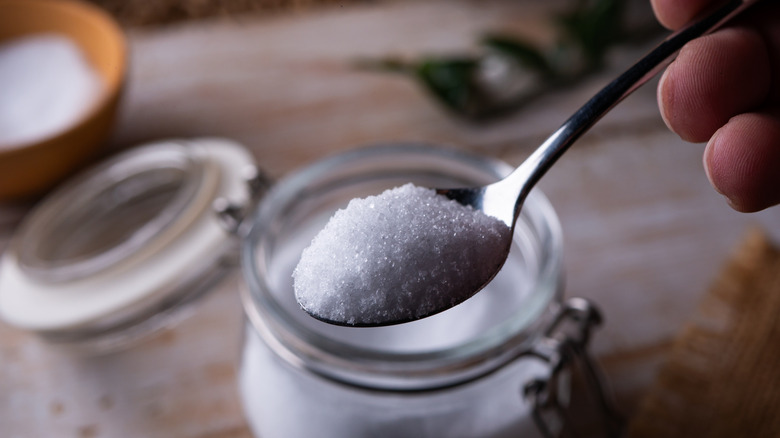 Spoon with erythritol above a bottle