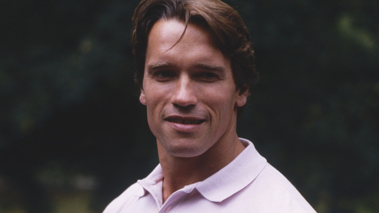 Arnold Schwarzenegger smiling in pink shirt