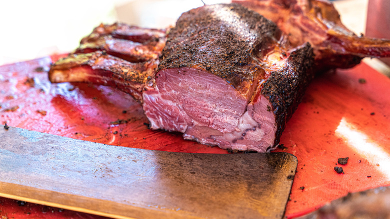 A rare rib bone roast being sliced on a cutting board