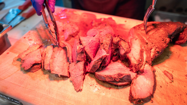 A piece of prime rib roast is carved up at a serving station
