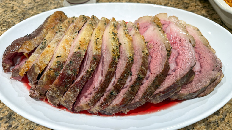 Prime rib sits in a puddle of its own juices on a serving platter